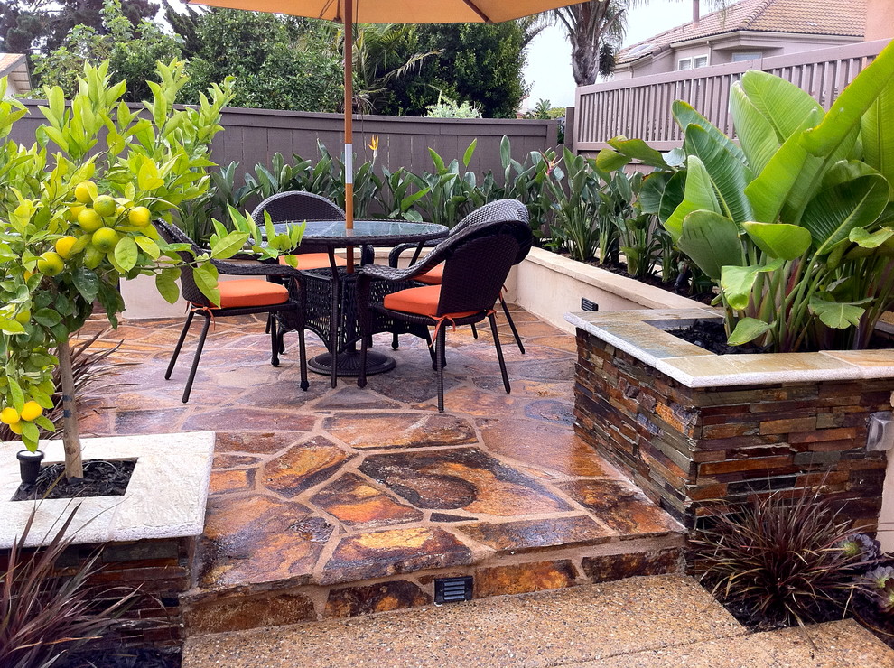 Eclectic patio in San Diego with natural stone pavers and no cover.
