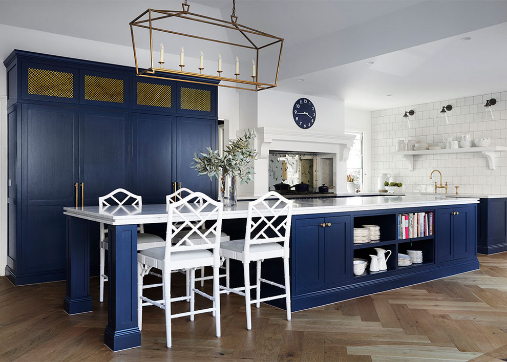 This is an example of a transitional kitchen in Melbourne with shaker cabinets, blue cabinets, white splashback, light hardwood floors, with island and white benchtop.