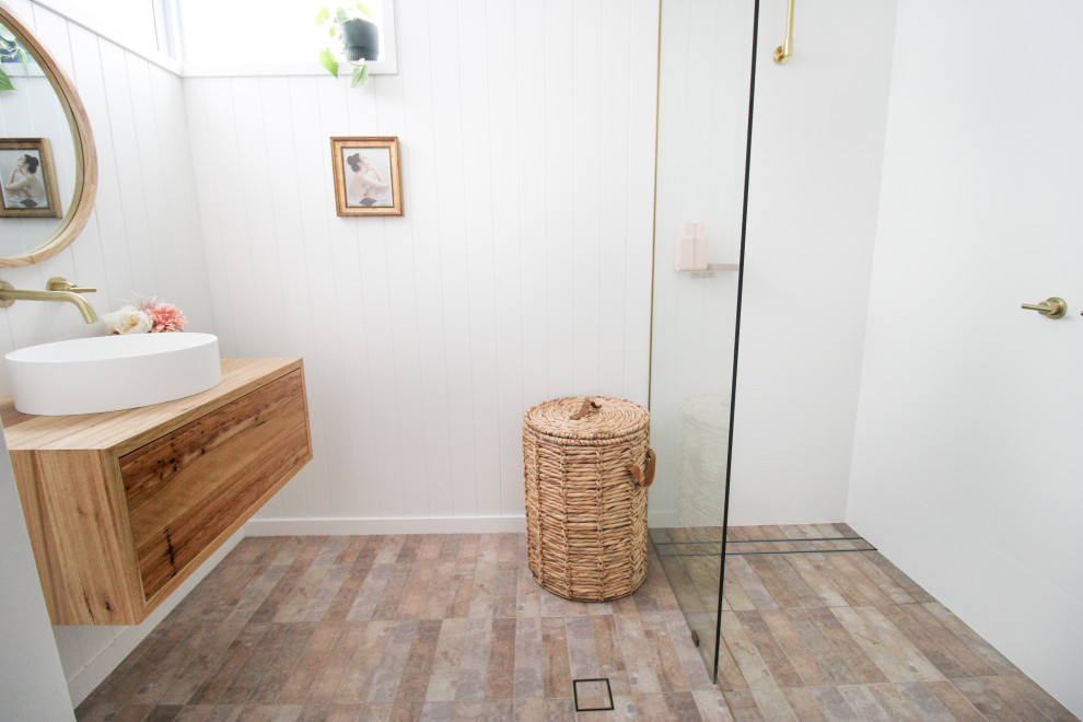 Inredning av ett nordiskt litet badrum med dusch, med släta luckor, skåp i mörkt trä, en öppen dusch, en toalettstol med hel cisternkåpa, vit kakel, keramikplattor, vita väggar, klinkergolv i porslin, ett fristående handfat, träbänkskiva, flerfärgat golv och med dusch som är öppen