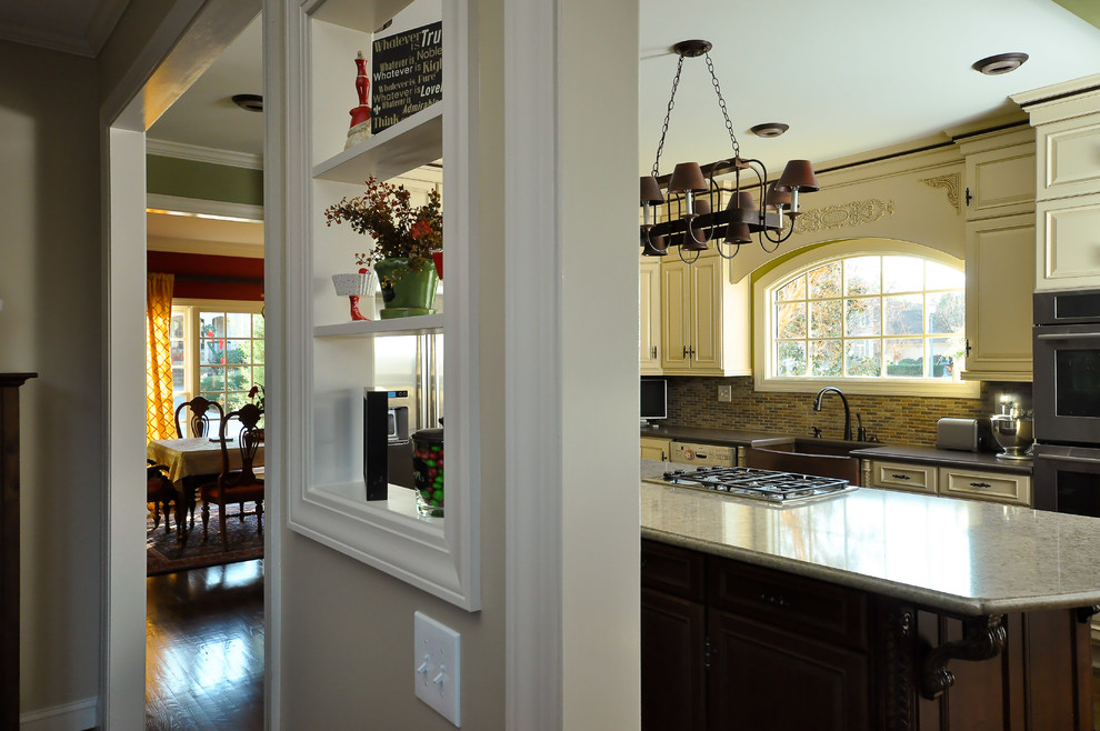 Example of a mid-sized transitional l-shaped dark wood floor eat-in kitchen design with a farmhouse sink, raised-panel cabinets, white cabinets, granite countertops, multicolored backsplash, mosaic tile backsplash, stainless steel appliances and an island