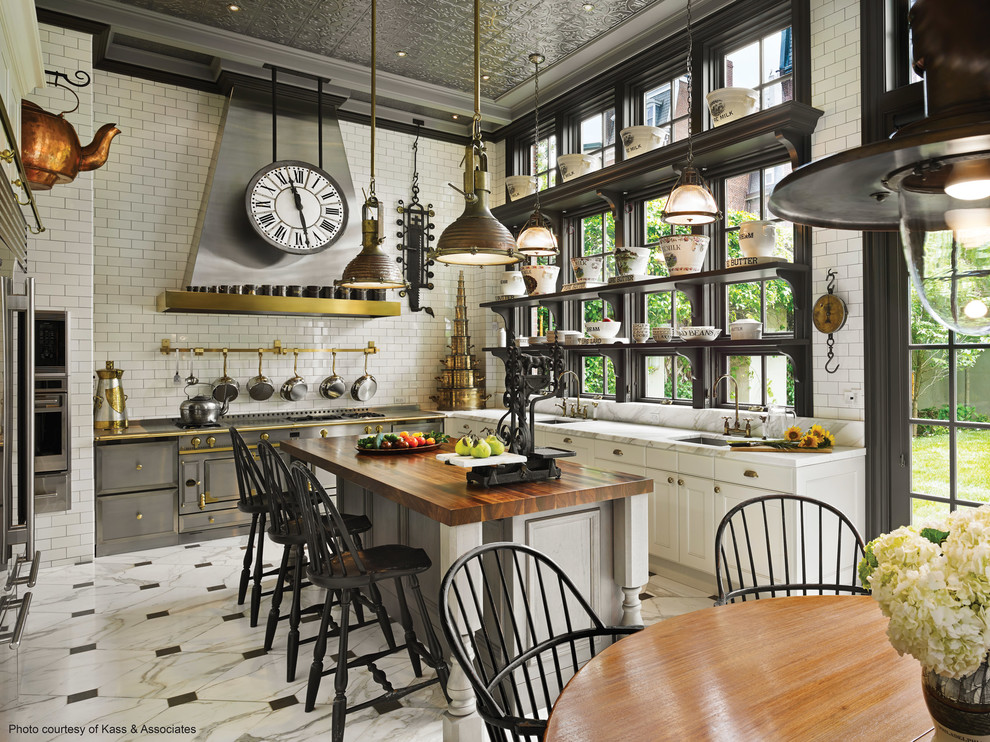 This is an example of a large industrial u-shaped eat-in kitchen in Minneapolis with shaker cabinets, white cabinets, white splashback, subway tile splashback, stainless steel appliances, marble floors, with island and white floor.