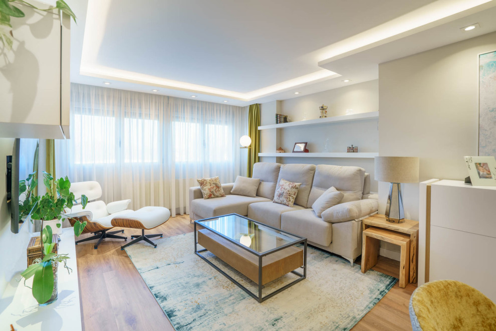 Immagine di un soggiorno minimal di medie dimensioni e chiuso con pareti beige, pavimento in laminato, TV a parete, pavimento marrone e soffitto ribassato