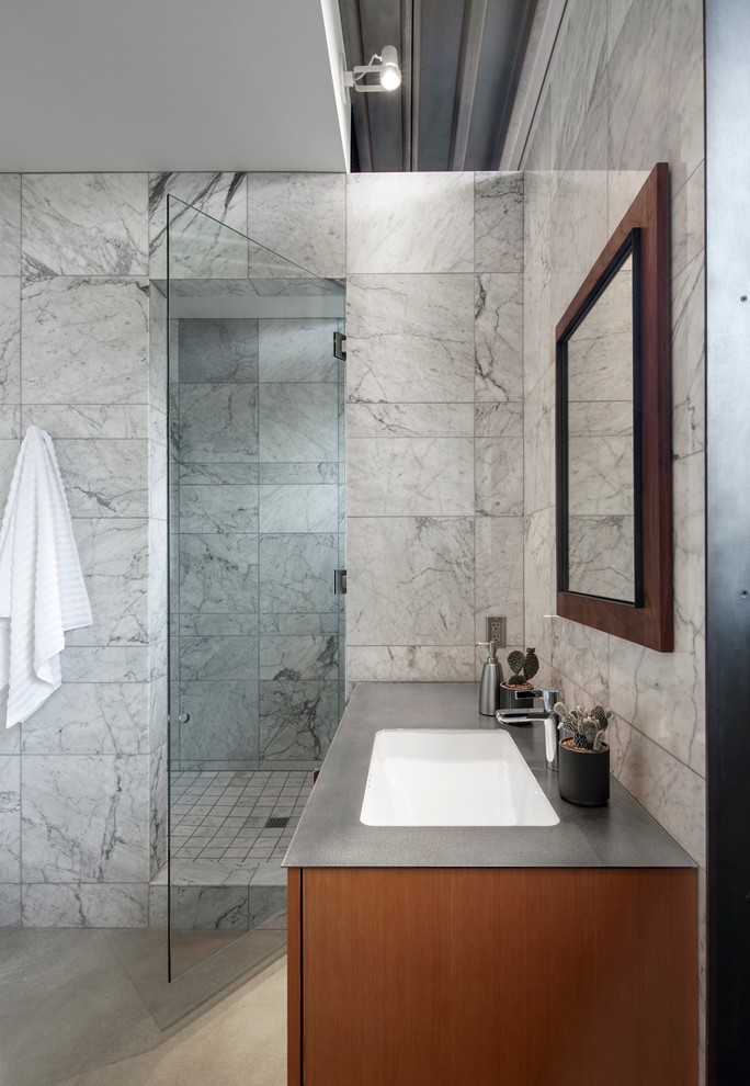 This is an example of a contemporary bathroom in Phoenix with an undermount sink, flat-panel cabinets, stainless steel benchtops, an open shower, stone tile, white walls and concrete floors.