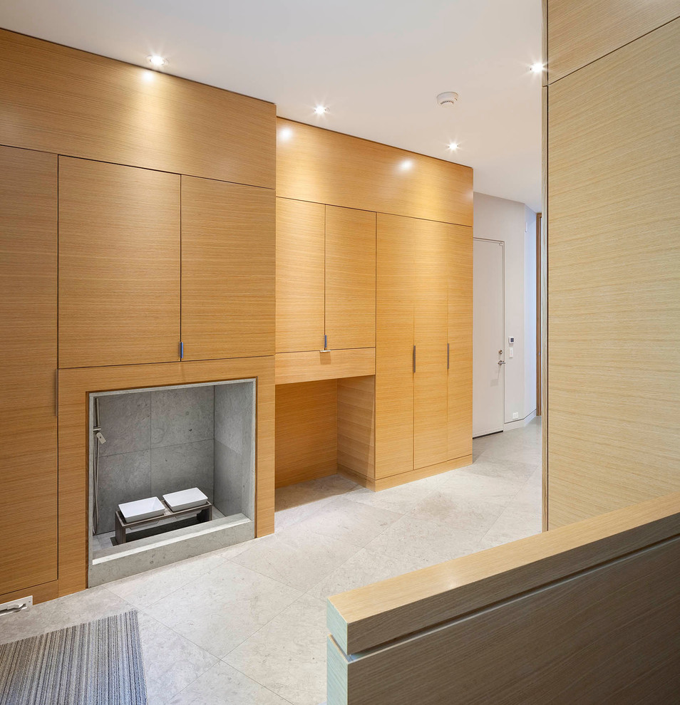Large modern gender-neutral walk-in wardrobe in Toronto with flat-panel cabinets, light wood cabinets and limestone floors.