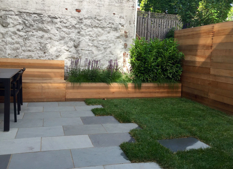 This is an example of a mid-sized contemporary backyard full sun garden in New York with natural stone pavers.