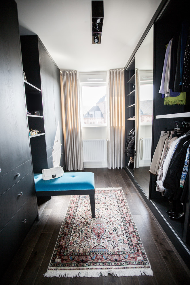 Photo of a large transitional gender-neutral dressing room in Nancy with dark wood cabinets and dark hardwood floors.
