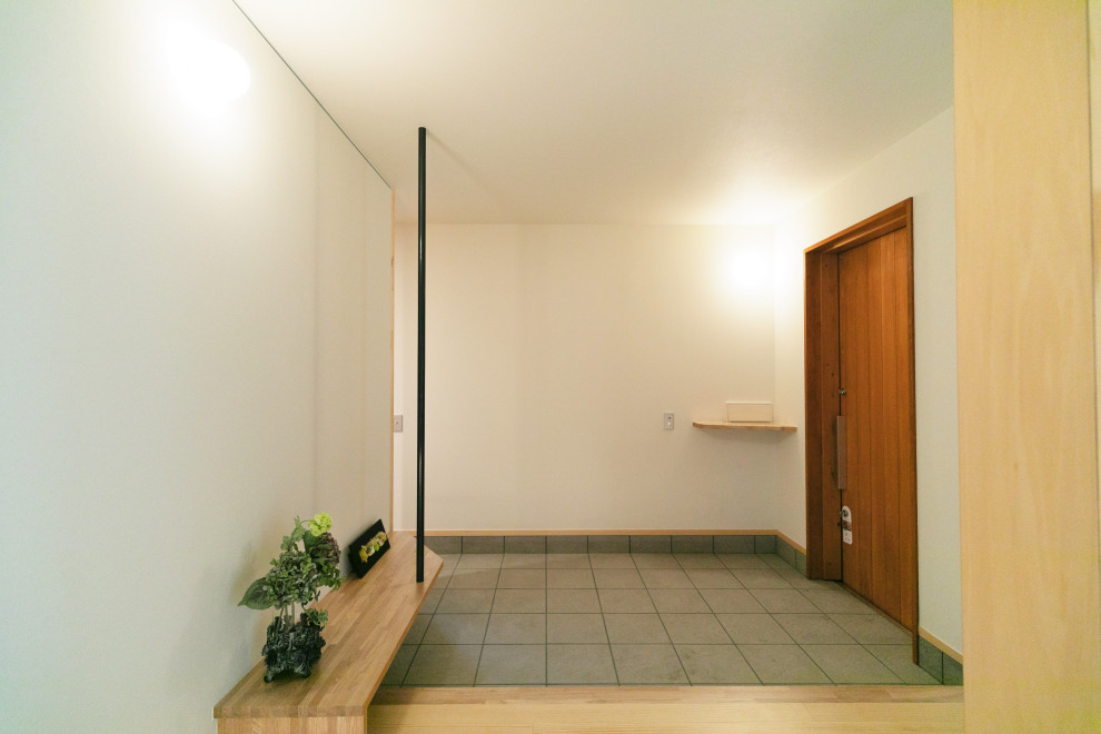 Foto på en mellanstor funkis hall, med vita väggar, klinkergolv i porslin, en skjutdörr, en brun dörr och grått golv