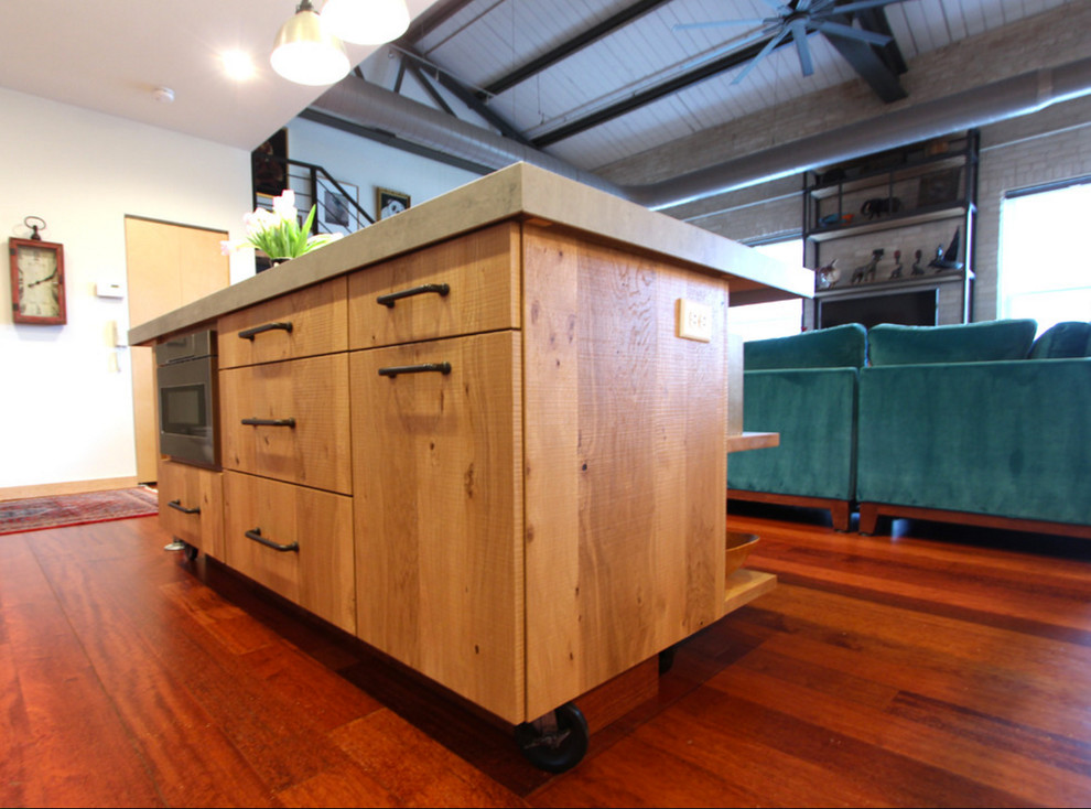 Industrial kitchen in Other with flat-panel cabinets, light wood cabinets, concrete benchtops, stainless steel appliances, dark hardwood floors, with island, red floor and grey benchtop.