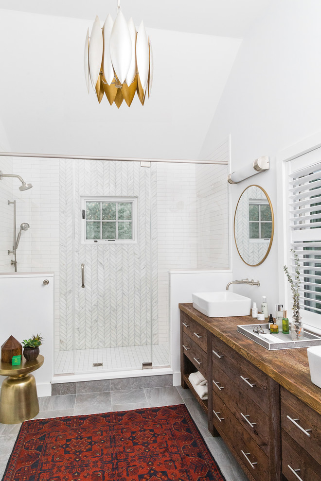Photo of a transitional bathroom in Boston with medium wood cabinets, an alcove shower, white tile, white walls, a vessel sink, wood benchtops, grey floor, a hinged shower door, brown benchtops and flat-panel cabinets.
