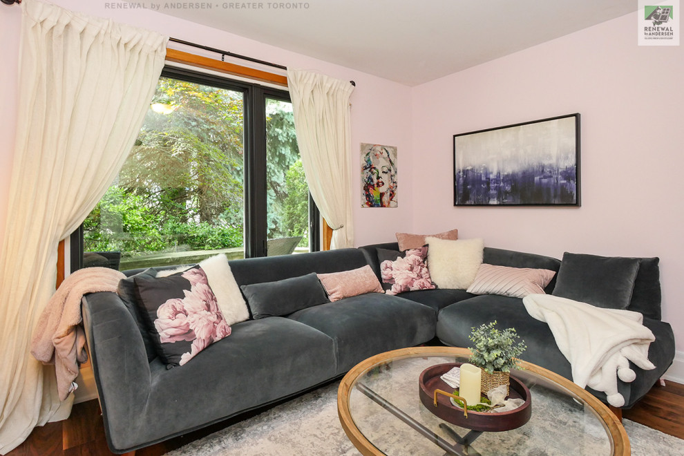 Cette image montre un salon de taille moyenne et fermé avec une salle de réception, un mur rose, un sol en bois brun, aucune cheminée, un téléviseur fixé au mur et un sol multicolore.