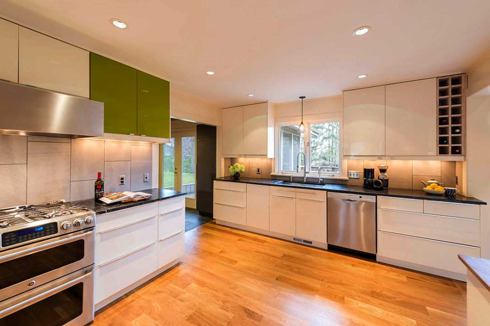 This is an example of a scandinavian u-shaped kitchen in Minneapolis with an undermount sink, flat-panel cabinets, white cabinets, marble benchtops, white splashback, stainless steel appliances, medium hardwood floors and black benchtop.
