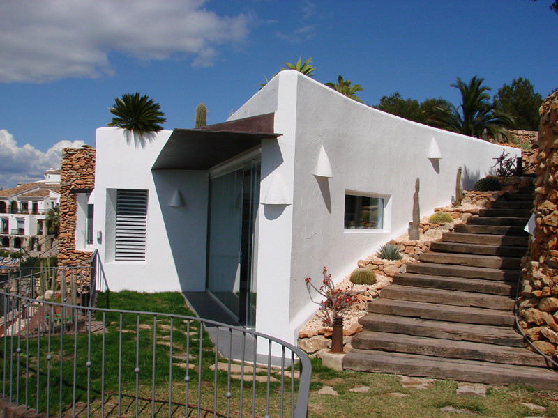 This is an example of a mid-sized mediterranean one-storey white house exterior in Alicante-Costa Blanca with mixed siding, a flat roof and a green roof.