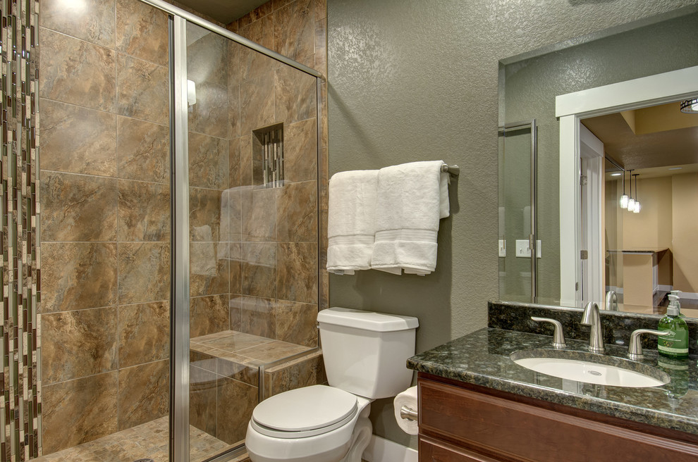 Photo of a mid-sized transitional 3/4 bathroom in Denver with raised-panel cabinets, dark wood cabinets, an alcove shower, a two-piece toilet, beige tile, ceramic tile, grey walls, an undermount sink, granite benchtops, a hinged shower door and black benchtops.