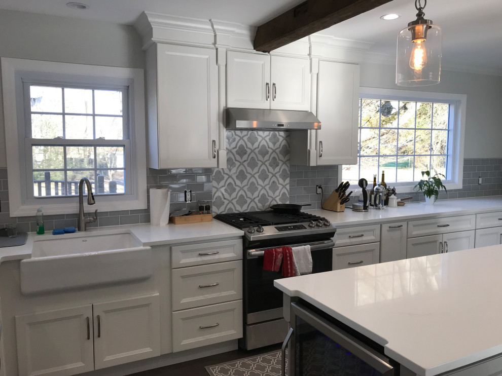 Example of a large transitional u-shaped ceramic tile and gray floor eat-in kitchen design with a farmhouse sink, recessed-panel cabinets, white cabinets, quartz countertops, gray backsplash, subway tile backsplash, stainless steel appliances, an island and white countertops