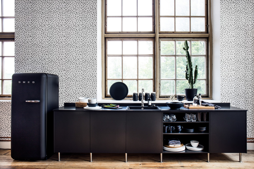 Inspiration for a modern kitchen in Gothenburg with a single-bowl sink, black cabinets, black appliances, beige floor and black benchtop.