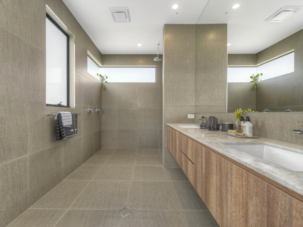 Photo of a contemporary 3/4 bathroom in Brisbane with medium wood cabinets, an open shower, beige tile, ceramic tile, beige walls, ceramic floors, a drop-in sink and marble benchtops.