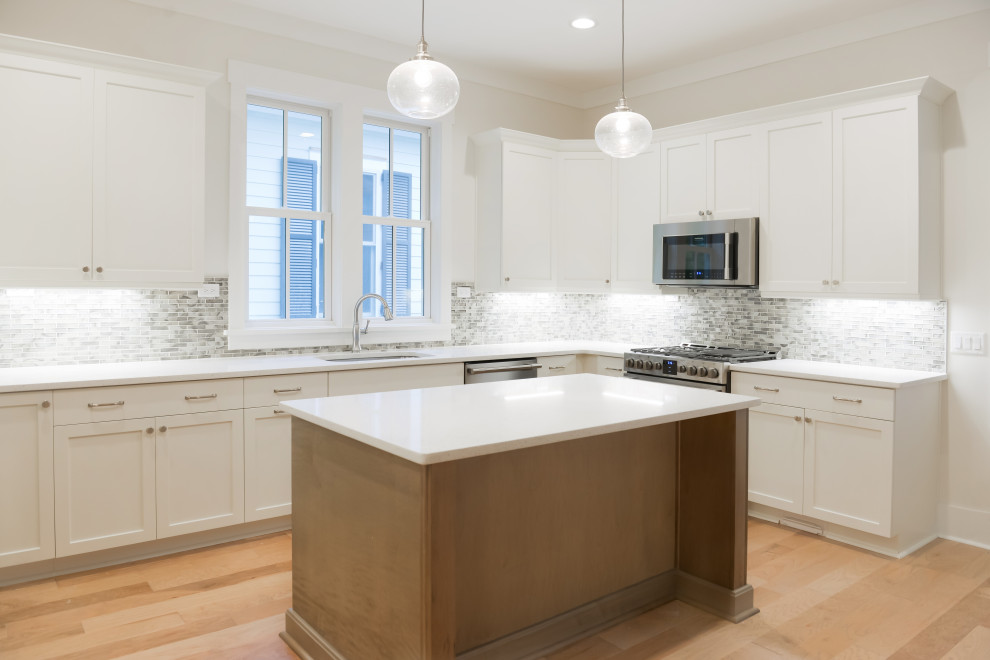 Example of a transitional kitchen design with stainless steel appliances and an island