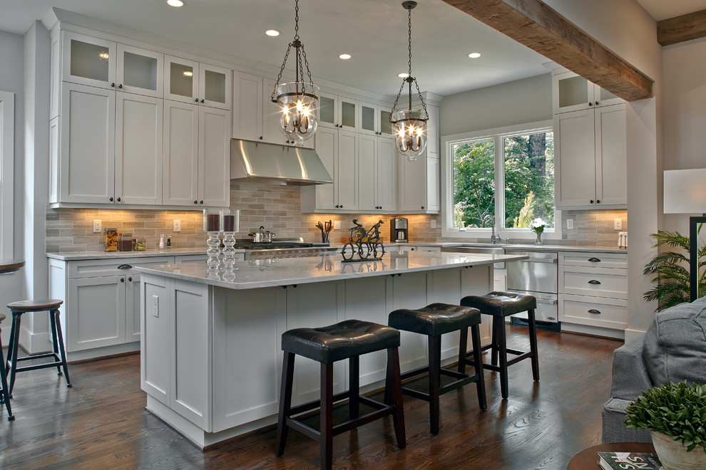 Large traditional l-shaped open plan kitchen in Atlanta with a farmhouse sink, shaker cabinets, white cabinets, marble benchtops, grey splashback, stainless steel appliances, dark hardwood floors, with island and white benchtop.