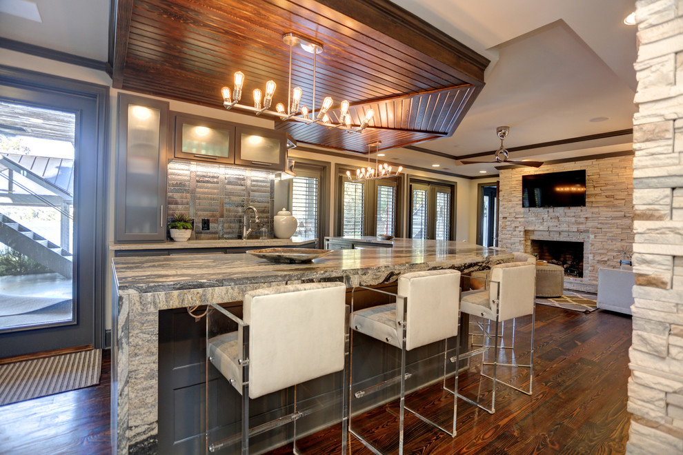 Inspiration for a large transitional galley seated home bar in Atlanta with an undermount sink, flat-panel cabinets, grey cabinets, granite benchtops, black splashback, glass tile splashback, dark hardwood floors and brown floor.