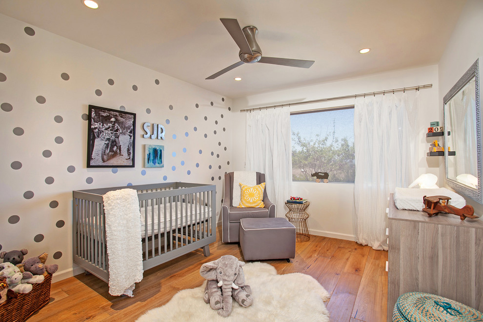 This is an example of a mid-sized transitional gender-neutral nursery in San Diego with white walls and light hardwood floors.