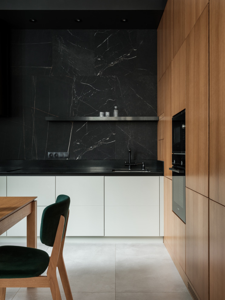 Photo of a mid-sized contemporary l-shaped eat-in kitchen in Saint Petersburg with an undermount sink, flat-panel cabinets, beige cabinets, solid surface benchtops, black splashback, porcelain splashback, black appliances, porcelain floors, no island, beige floor and black benchtop.