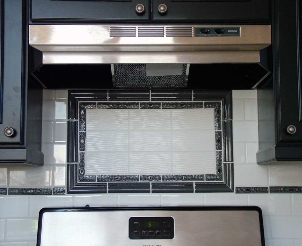 Example of a mid-sized transitional u-shaped light wood floor open concept kitchen design in Denver with an undermount sink, beaded inset cabinets, black cabinets, marble countertops, white backsplash, subway tile backsplash, stainless steel appliances and a peninsula