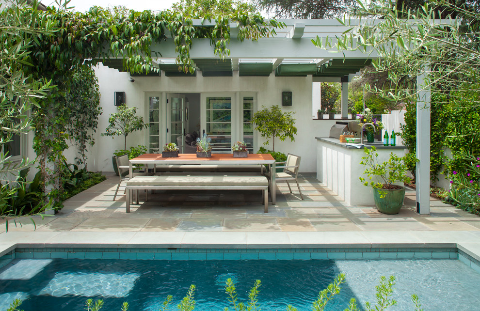 Inspiration for a mid-sized mediterranean backyard patio in Los Angeles with an outdoor kitchen, a pergola and concrete pavers.