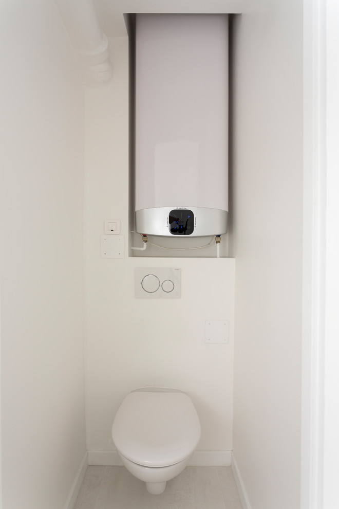 Photo of a mid-sized modern powder room in Paris with white walls, open cabinets, white cabinets, a wall-mount toilet, white tile, vinyl floors, grey floor and white benchtops.