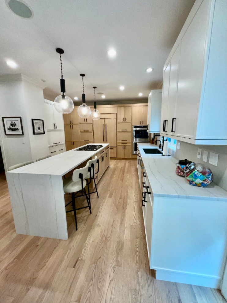 Mid-sized transitional kitchen photo in Chicago with light wood cabinets, quartzite countertops, white backsplash, stone slab backsplash, paneled appliances, an island and white countertops