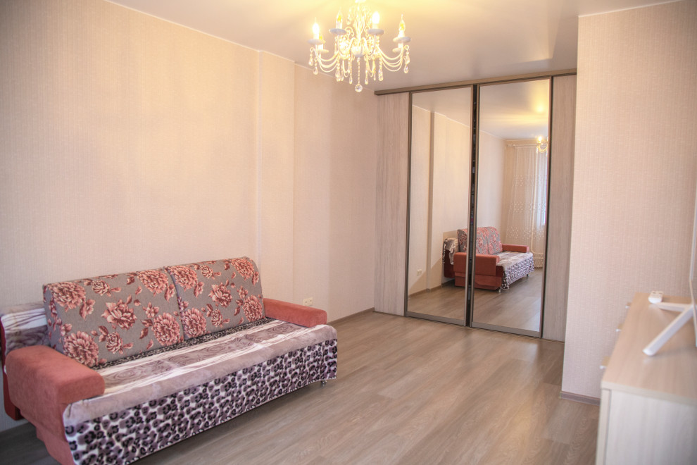 На фото: гостиная комната среднего размера с розовыми стенами, полом из ламината, коричневым полом и обоями на стенах с