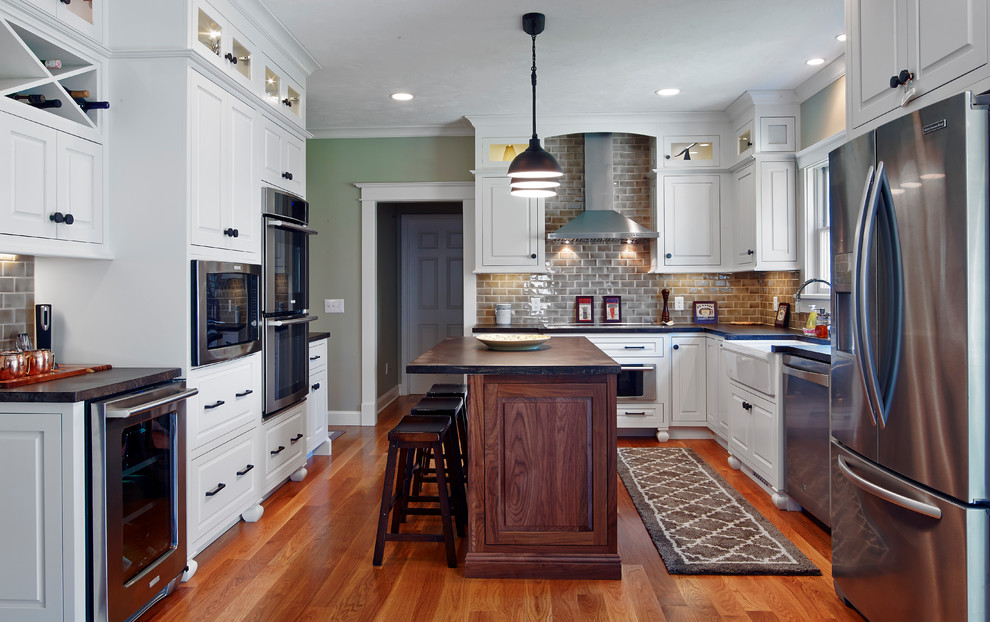 Inspiration for a mid-sized traditional u-shaped separate kitchen in Providence with a farmhouse sink, raised-panel cabinets, white cabinets, grey splashback, subway tile splashback, stainless steel appliances, medium hardwood floors, with island and brown floor.