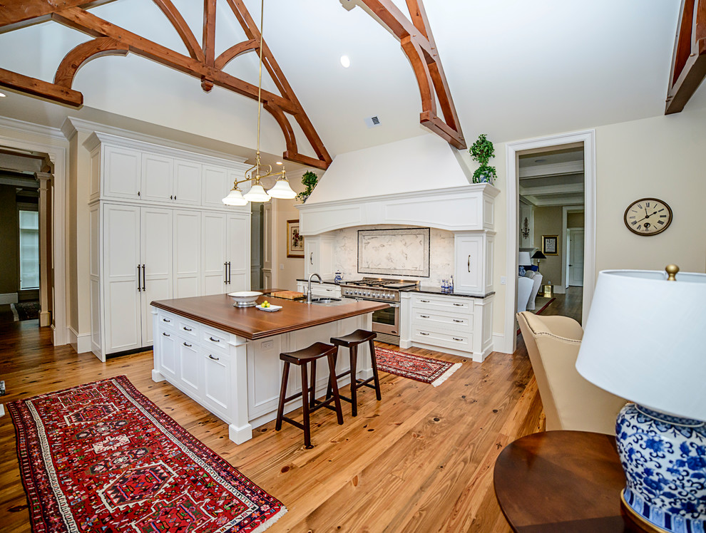 Example of a transitional medium tone wood floor kitchen design in Atlanta with an undermount sink, granite countertops, white backsplash, stainless steel appliances and an island