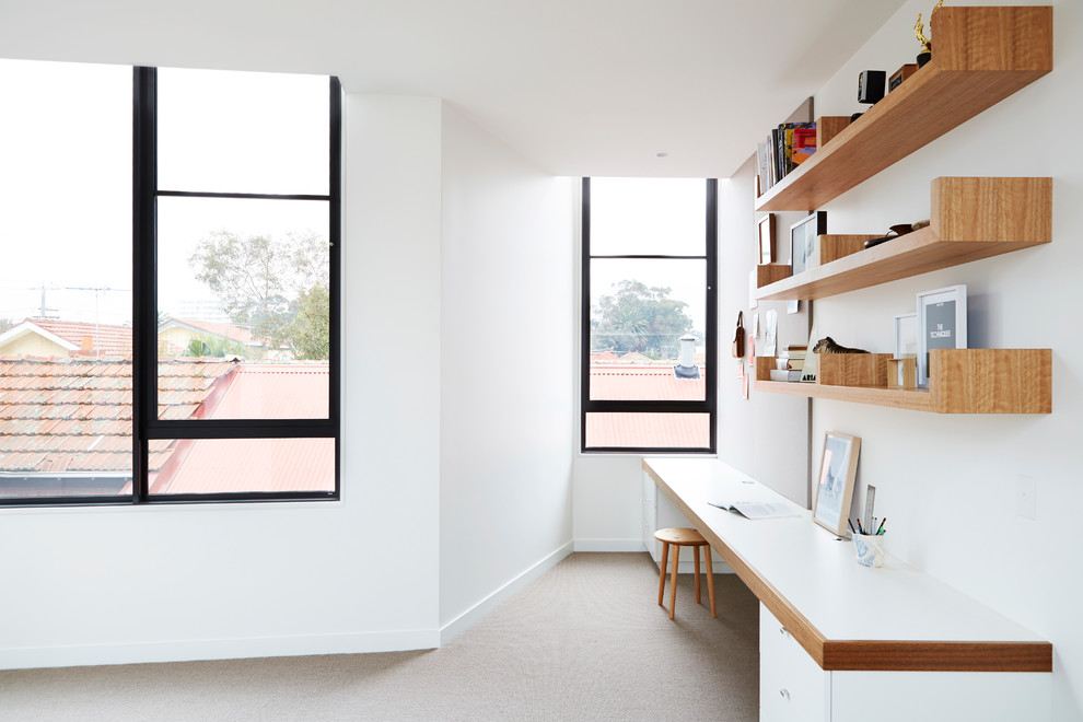 This is an example of a contemporary study room in Melbourne with white walls, carpet and a built-in desk.