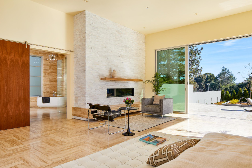 Cette image montre une très grande chambre parentale minimaliste en bois avec un mur beige, un sol en travertin, une cheminée standard, un manteau de cheminée en pierre, un sol beige et un plafond en bois.