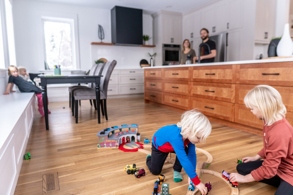 Inspiration for a large transitional l-shaped medium tone wood floor and multicolored floor eat-in kitchen remodel with shaker cabinets, medium tone wood cabinets, quartz countertops, white backsplash, stone slab backsplash, stainless steel appliances, an island and white countertops