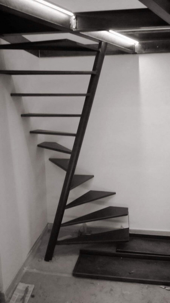 Small industrial metal spiral staircase in Rome with open risers and metal railing.