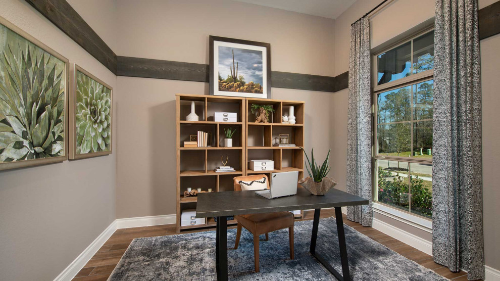 Freestanding desk medium tone wood floor and brown floor study room photo in Houston with beige walls