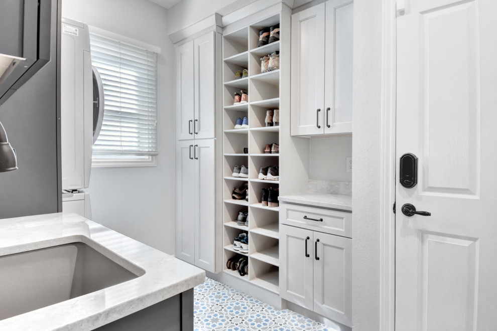 Rural u-shaped utility room in Denver with an utility sink, shaker cabinets, white cabinets, granite worktops, ceramic flooring, a stacked washer and dryer and white worktops.