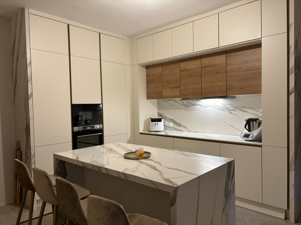 Photo of a large contemporary u-shaped separate kitchen in Other with an integrated sink, beaded inset cabinets, beige cabinets, tile benchtops, beige splashback, marble splashback, panelled appliances, ceramic floors, with island, grey floor and beige benchtop.