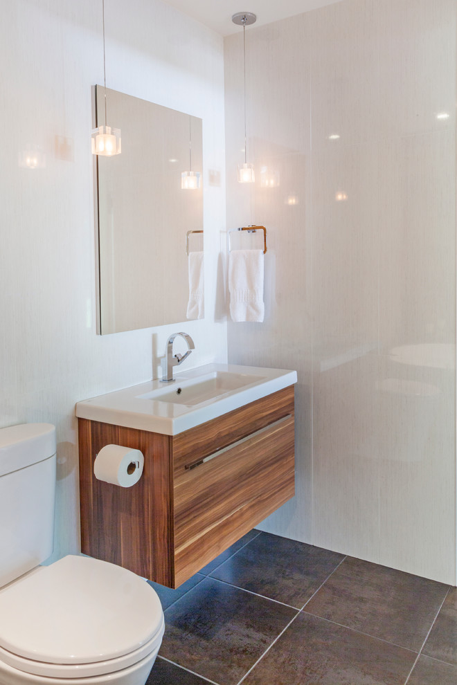 Design ideas for a mid-sized contemporary master bathroom in New York with flat-panel cabinets, light wood cabinets, a freestanding tub, a two-piece toilet, white walls, slate floors, an integrated sink and solid surface benchtops.