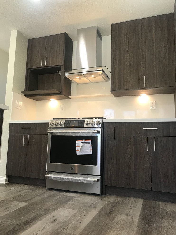 Mid-sized contemporary l-shaped open plan kitchen in San Francisco with an undermount sink, flat-panel cabinets, dark wood cabinets, quartz benchtops, white splashback, stainless steel appliances, dark hardwood floors, with island, brown floor, white benchtop and glass sheet splashback.