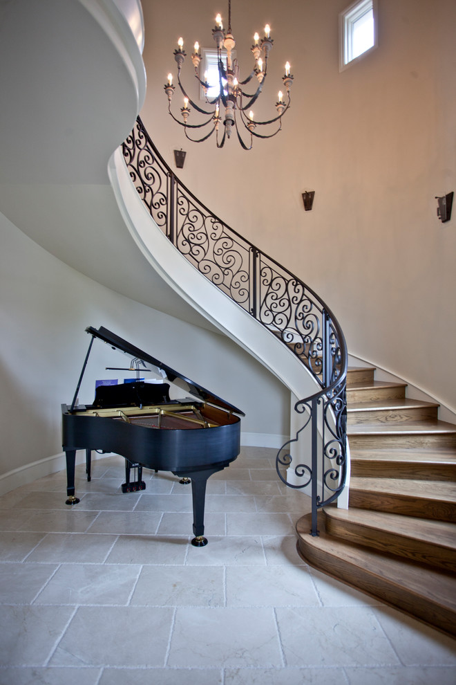 Photo of a large mediterranean wood curved staircase in Other with wood risers and metal railing.