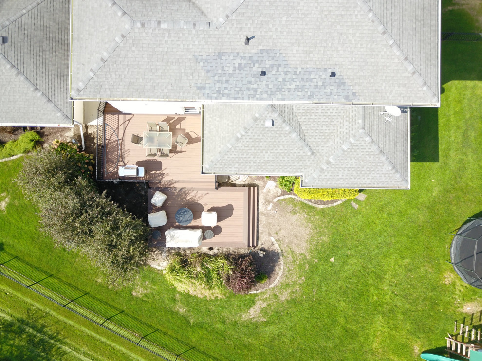 Inspiration for a large backyard ground level metal railing deck remodel with a roof extension