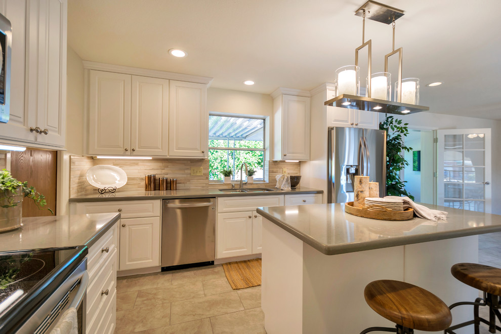 Inspiration for a large transitional l-shaped porcelain tile open concept kitchen remodel in Phoenix with an undermount sink, raised-panel cabinets, white cabinets, quartz countertops, beige backsplash, porcelain backsplash, stainless steel appliances and an island