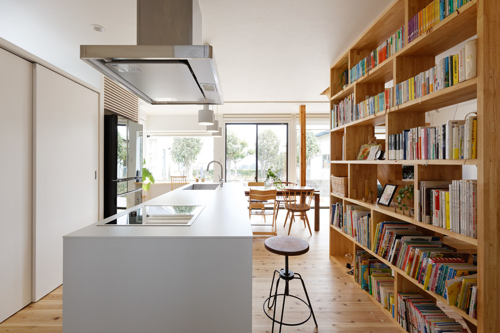 Design ideas for a contemporary open plan kitchen in Tokyo with an undermount sink, flat-panel cabinets, white cabinets, white splashback, stainless steel appliances, with island, brown floor and light hardwood floors.
