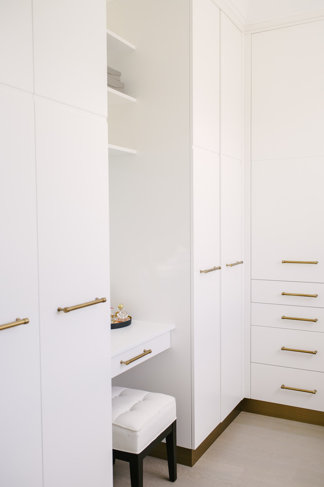 This is an example of a mid-sized contemporary gender-neutral walk-in wardrobe in Toronto with flat-panel cabinets, white cabinets, light hardwood floors and beige floor.