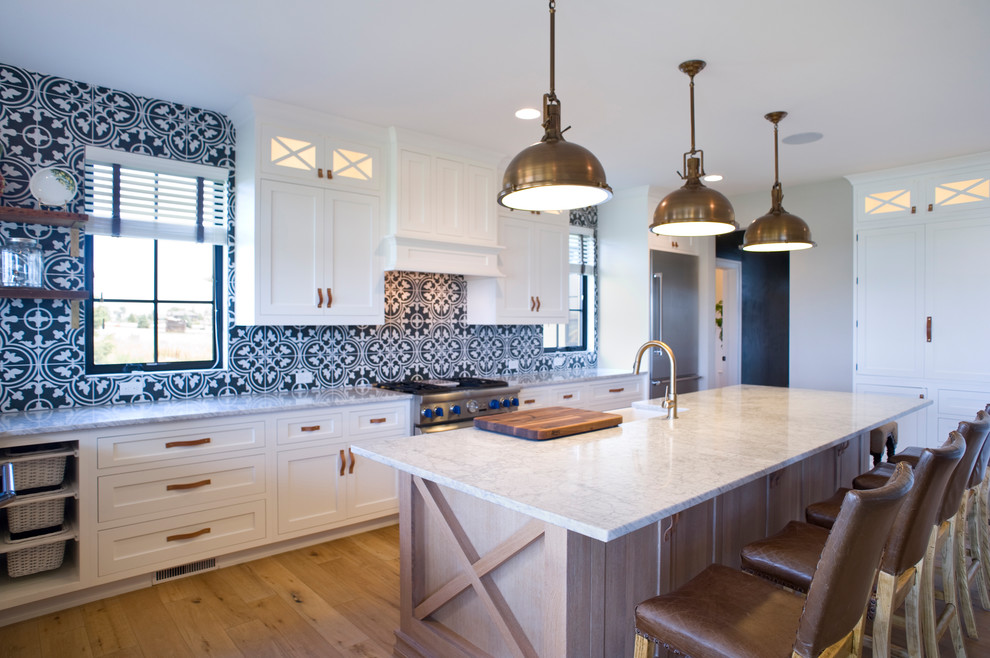 Eat-in kitchen - large transitional u-shaped light wood floor and brown floor eat-in kitchen idea with raised-panel cabinets, white cabinets, marble countertops, multicolored backsplash, porcelain backsplash, stainless steel appliances and an island