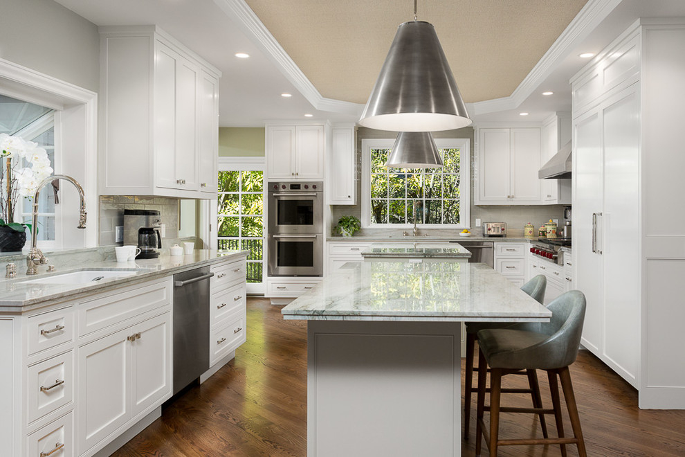 Design ideas for a traditional kitchen in Los Angeles with shaker cabinets, white cabinets, medium hardwood floors and multiple islands.