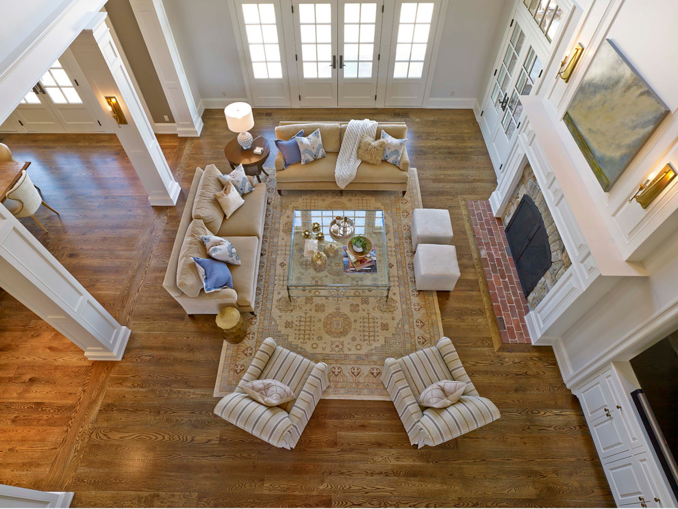 This is an example of a large traditional open concept living room in Philadelphia with white walls, medium hardwood floors, a standard fireplace, a stone fireplace surround and brown floor.