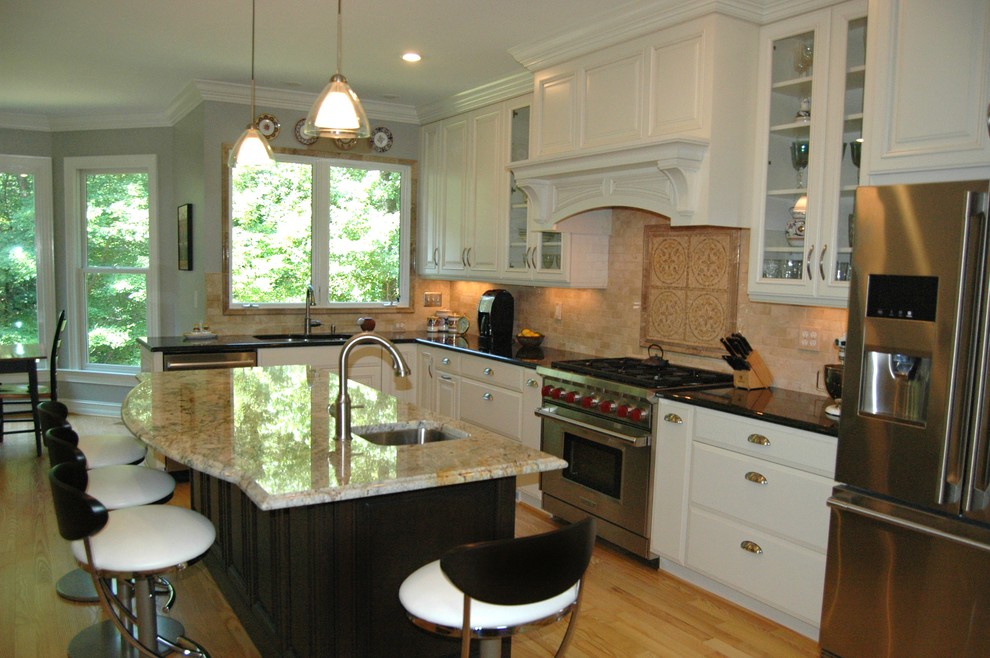 This is an example of a transitional kitchen in Raleigh with raised-panel cabinets, white cabinets, granite benchtops, beige splashback, stainless steel appliances and light hardwood floors.